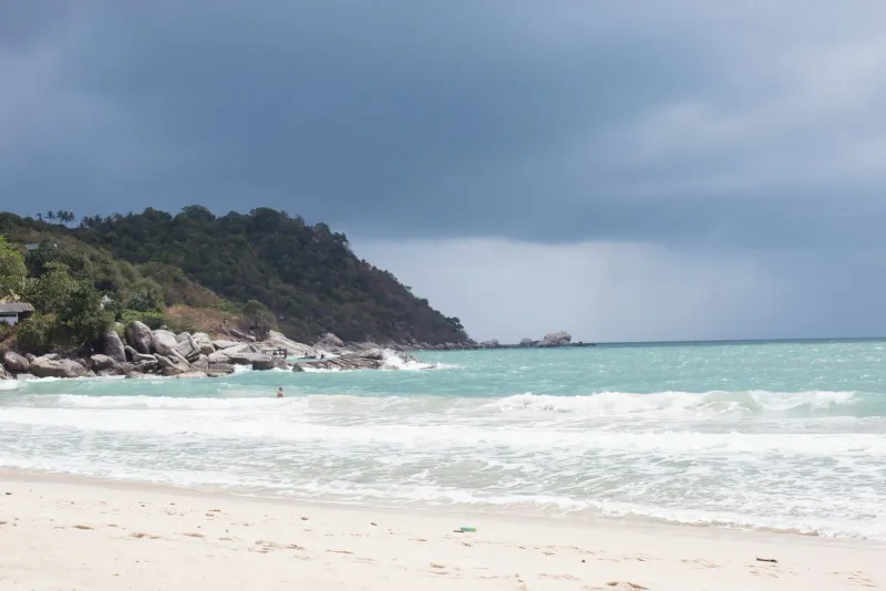 Rolling waves under dramatic clouds on a Koh Samui-style tropical coastline