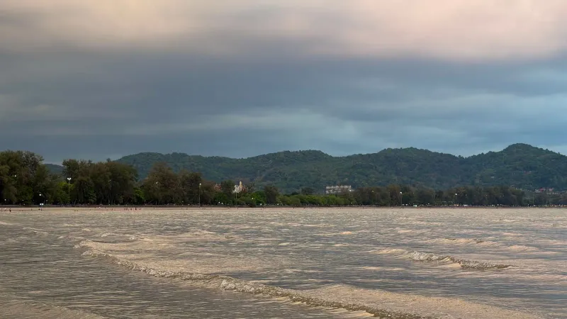 Golden hour light over a calm bay with distant hills, illustrating clear dry-season water conditions