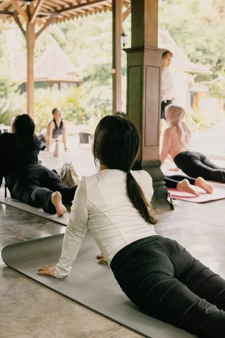 Adults holding yoga poses outdoors in a calm tropical setting on Koh Samui