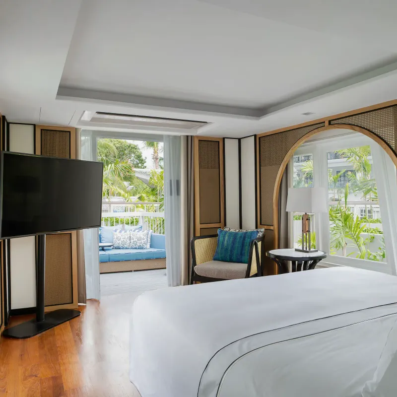 Bedroom in a Melia Koh Samui boat suite with rattan arched panels, teak floor and a terrace sofa