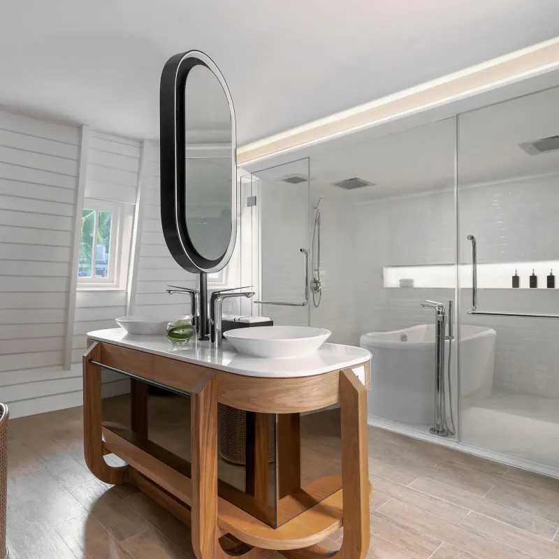 Suite bathroom at Melia Koh Samui with twin basins, oval mirror, glass shower and freestanding bath