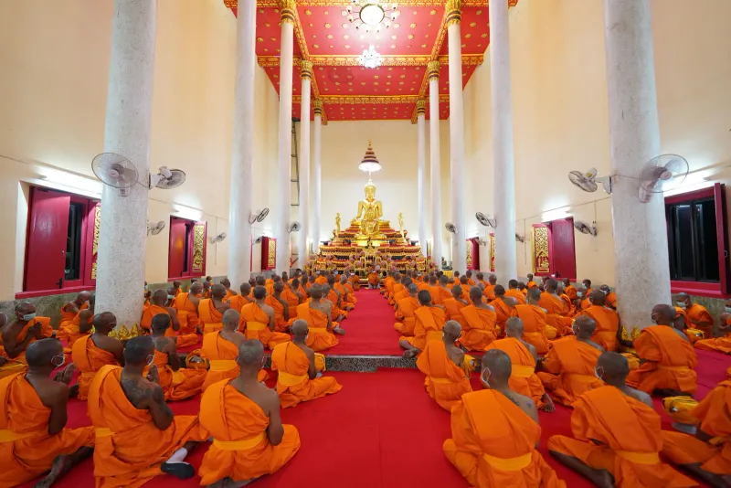 Rows of monks chanting in a temple hall