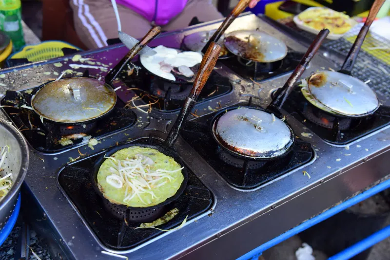 Pancakes frying on a row of griddles