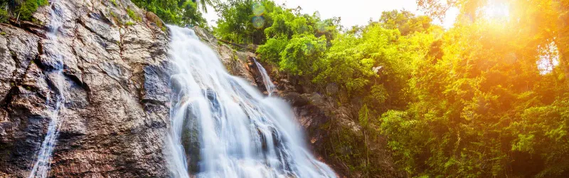 Na Muang waterfall cascading through the rocks in golden afternoon light