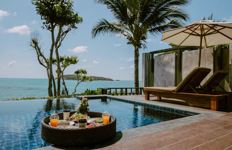 Floating breakfast tray beside a private infinity pool facing the sea at Nora Buri Resort