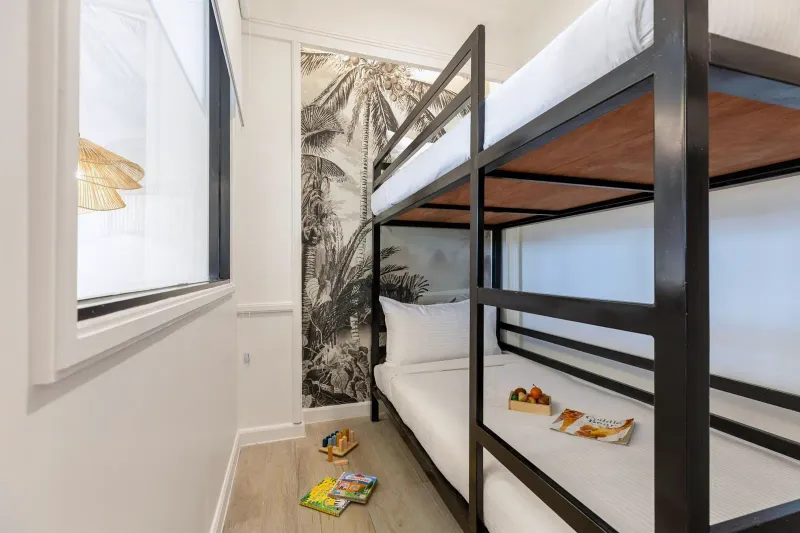 Family room at Outrigger Koh Samui with built-in bunk beds, jungle-print wallpaper and children's books