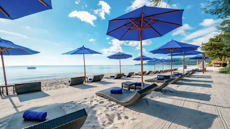 Blue parasols and sunbeds on the white sand of Chaweng beach in front of OZO Chaweng Samui