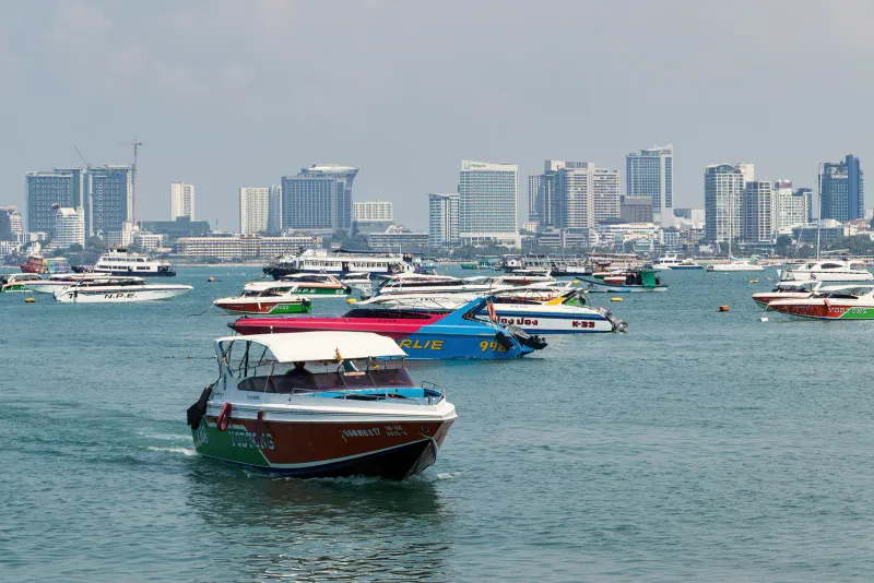 Speedboats anchored in Pattaya bay with high-rise hotels along the waterfront behind
