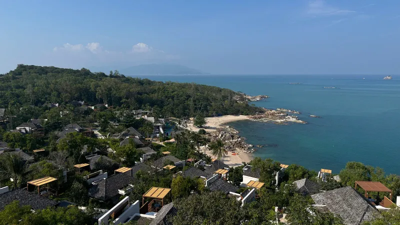 Elevated view of the resort roofs, small sandy beach and rocky shoreline on the private bay
