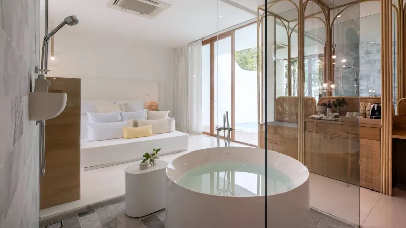 Bathroom in a garden pool villa at SALA Samui Chaweng with a freestanding round tub beside a glass wall