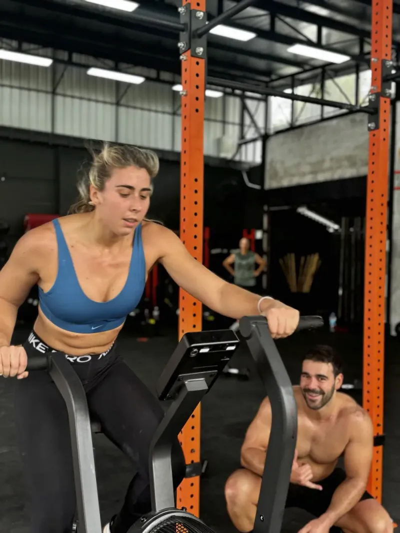 A woman training on a cardio machine beside an orange rig post