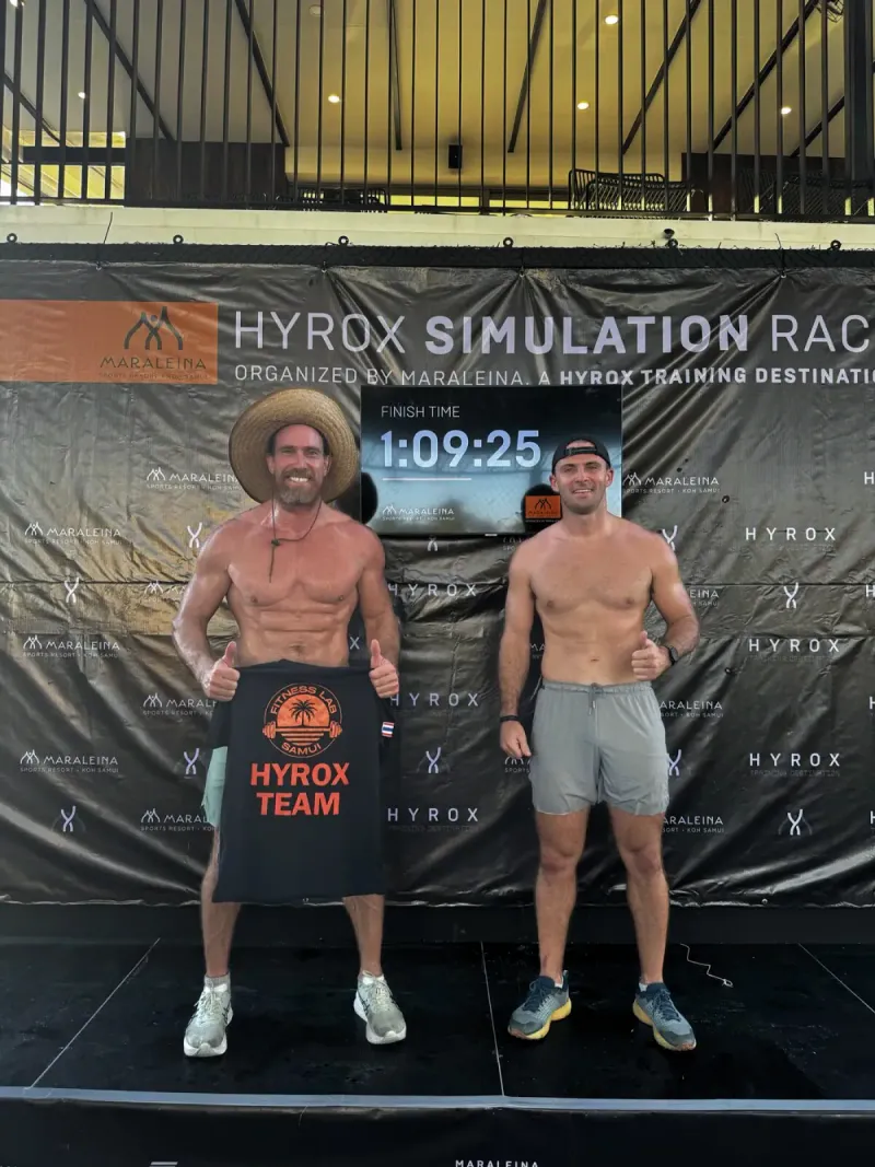 Two athletes smiling in front of a HYROX simulation race banner with a finish time of 1:09:25