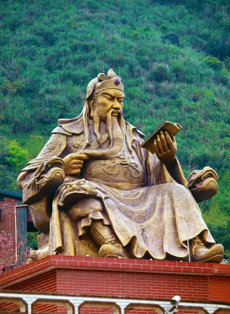 A stunning bronze statue of Guan Yu in Jinguashi, Taiwan against a lush green backdrop