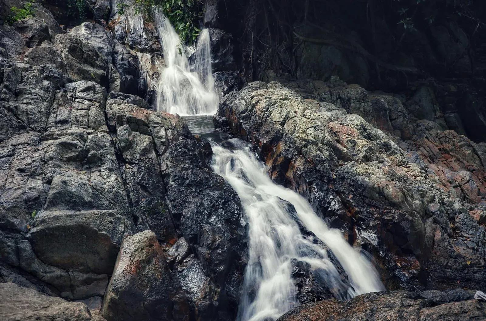 Na Muang 1 Waterfall's purple-tinted rock face dropping into a swimming pool