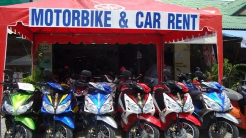Roadside Thai motorbike and car rental stand with scooters lined up under a canopy