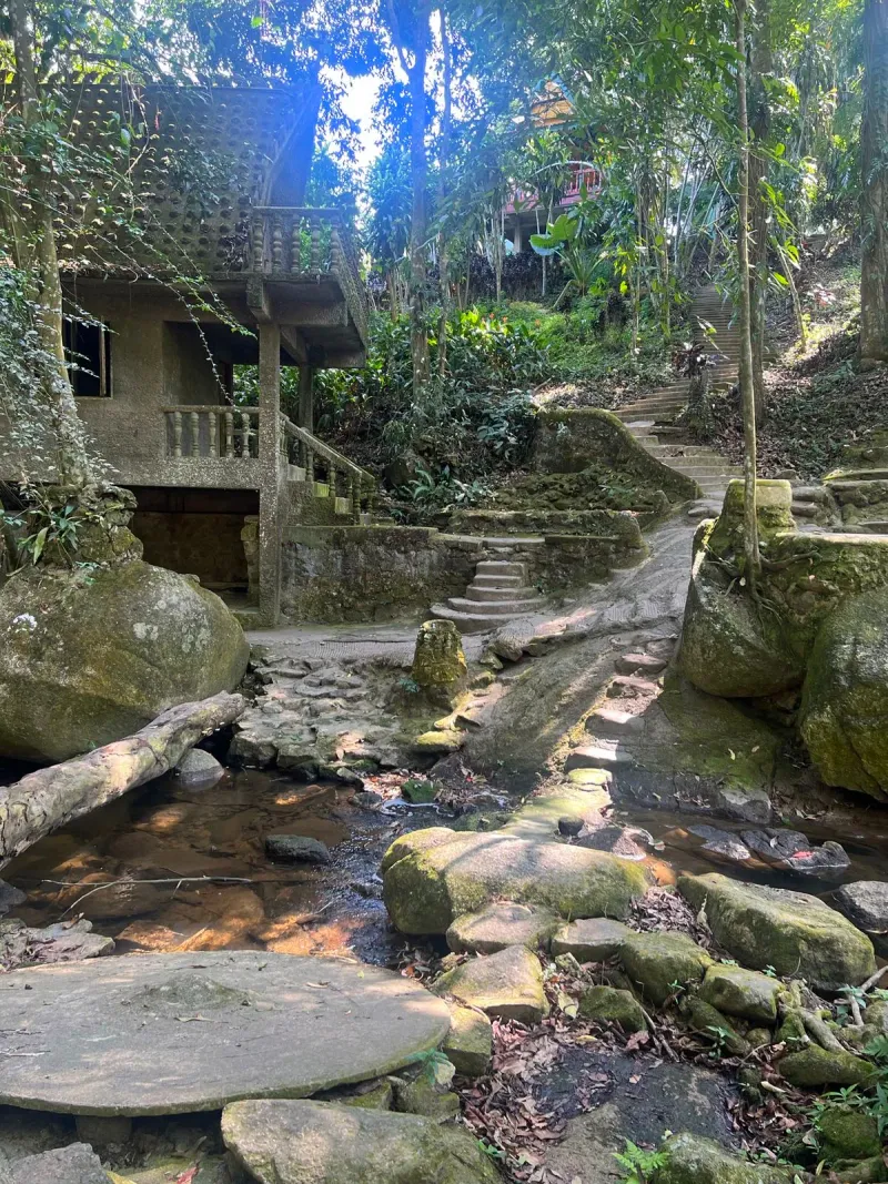 Stone stairway winding past a traditional hut in the Secret Buddha Garden