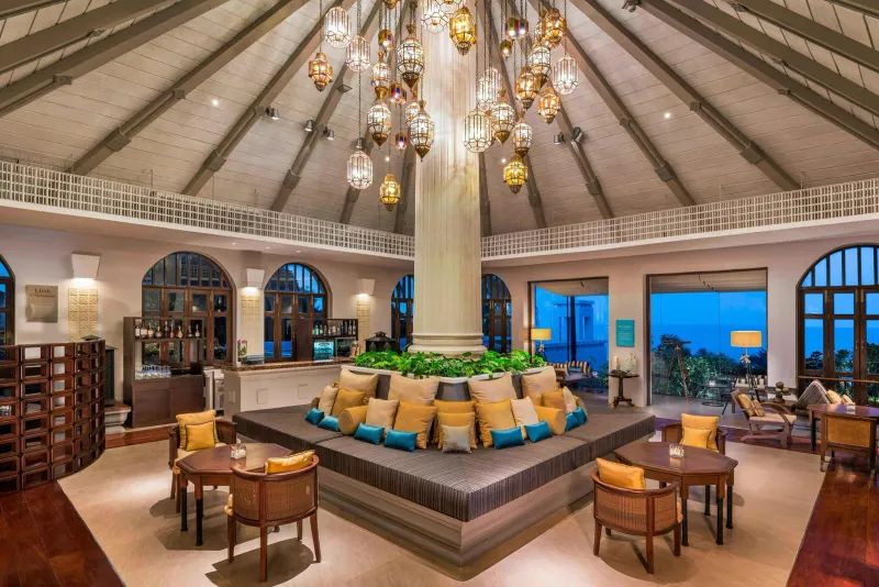 Lobby lounge with a central column, brass lanterns and a circular sofa at Sheraton Samui Resort