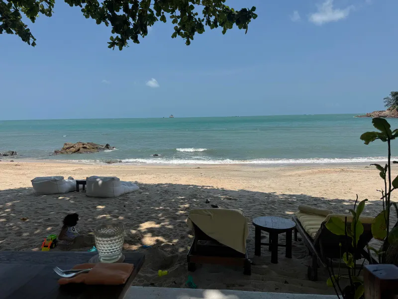 Sandy beach at Samrong Bay on Koh Samui with lounge chairs and a calm turquoise sea