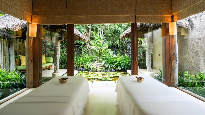 Couple's treatment room at Six Senses Samui spa with two massage beds facing a garden pond