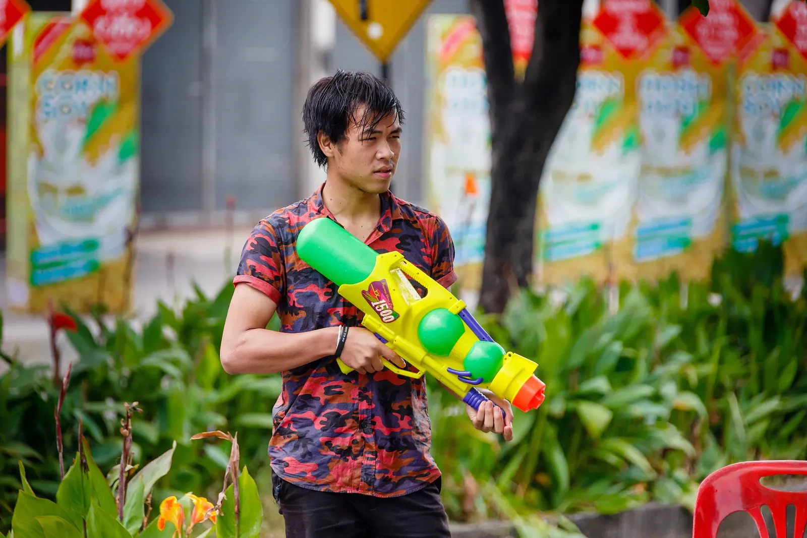 Young man with a colourful water gun during Songkran in Thailand