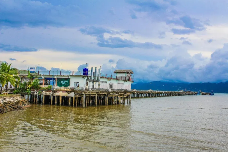 Long concrete pier extending into the sea with a ferry terminal building