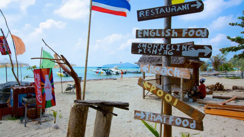 Beach signpost pointing to a restaurant and snorkeling near Taling Ngam
