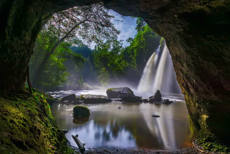 Jungle waterfall framed by a cave-like rock opening