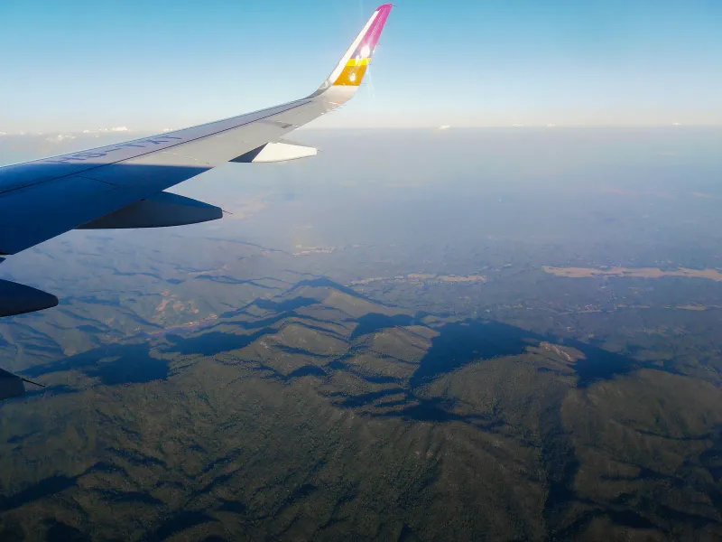 Airliner wing over forested hills seen from a window seat on a domestic flight in Thailand