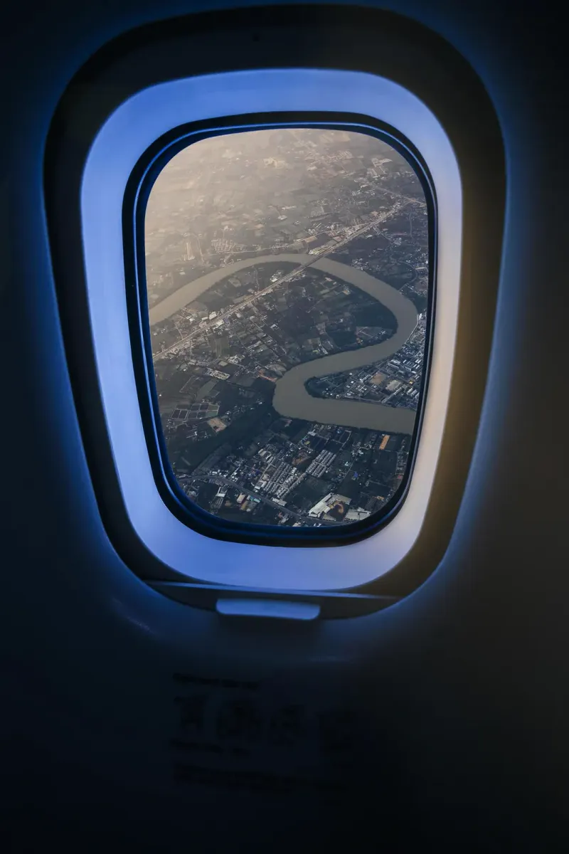 River winding through farmland and suburbs seen from an airliner window over Thailand
