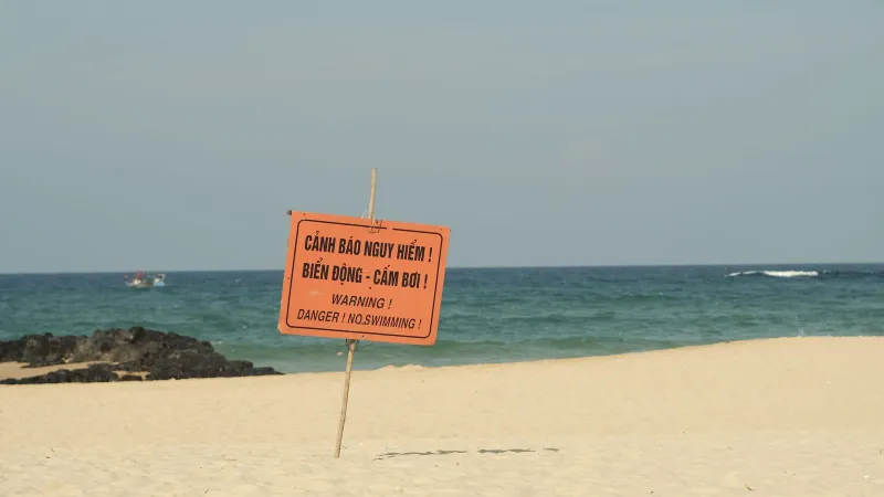 No swimming warning sign posted on a sandy Thailand beach near the shoreline