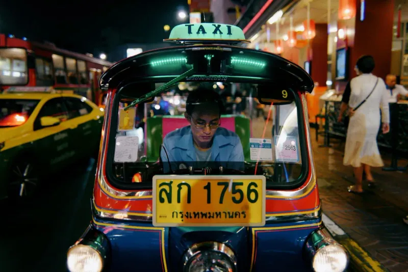 Thai taxi driver navigating a busy street where fares are rarely metered