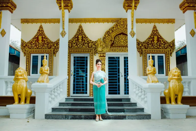 Visitor in modest traditional dress standing at an ornate Thai temple entrance in Koh Samui