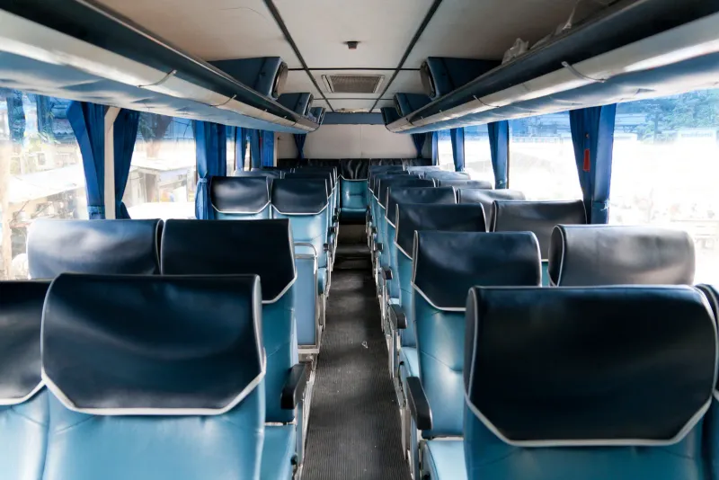 Interior of an intercity coach in Thailand with rows of blue reclining seats and curtains