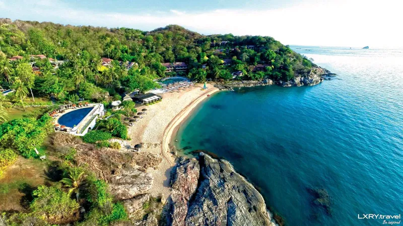 Aerial view of Tong Sai Bay's curved cove, pool and hillside resort buildings