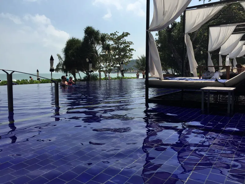 Vana Belle infinity pool with shaded daybeds and sun umbrellas facing the sea on Koh Samui