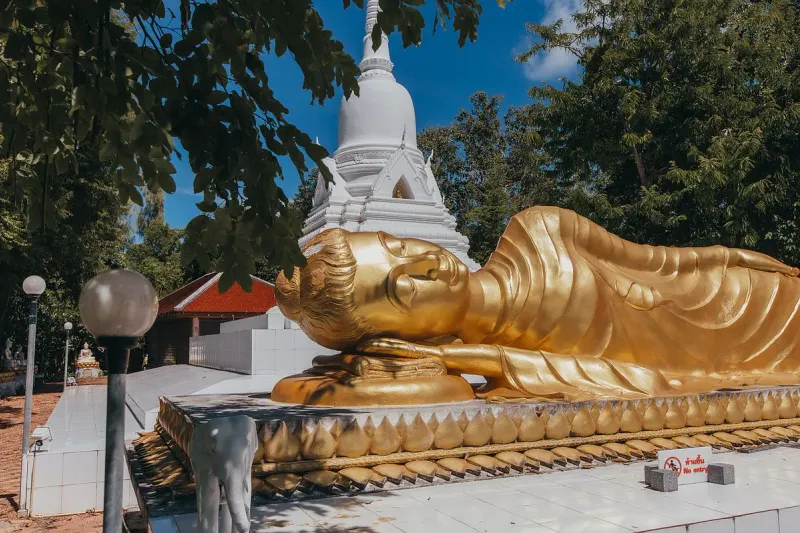 Close view of the reclining Buddha's head beneath the white chedi's spire