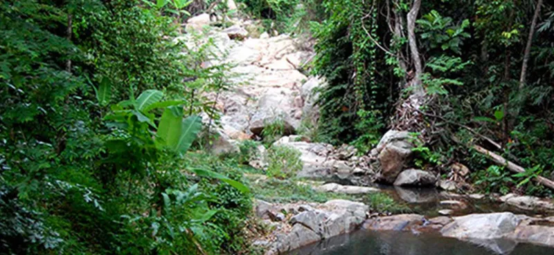 Boulder-lined approach to Zong Raue Waterfall with a small pool at the base